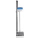 A digital scale with a white rectangular surface and a tall white pole with a black handle.