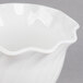 A white Cambro polycarbonate bowl with a wavy edge on a gray surface.