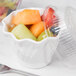 A white plastic Cambro swirl bowl filled with fruit.