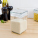 A clear Anchor Hocking stackable glass jar filled with rice and pasta on a kitchen counter.