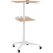 A natural wood and beige Safco adjustable height mobile workstation with wheels.