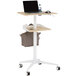 A Safco natural wood mobile standing workstation with a laptop on it.