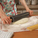 A person using a Fox Run black marble rolling pin to roll out dough on a countertop.