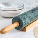 A Fox Run green marble rolling pin on a wooden stand.