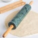 A Fox Run rolling pin with green marble on the ends and wooden handles.
