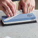A person sharpening a knife on a Mercer Culinary combination sharpening stone on a counter.