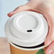 A hand putting a white EcoChoice Compostable sugarcane hot cup lid on a coffee cup.