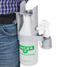 A person wearing a Unger sprayer system with a white bottle and green label in a belt clip.