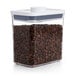 An OXO Good Grips rectangular plastic food storage container filled with coffee beans and a white lid.