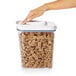 A hand holding an OXO Good Grips plastic container with cereal.
