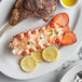 A plate with a Boston Lobster Company 20-24 oz. lobster tail and steak on it.