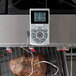 A piece of meat cooking on a grill with a CDN digital thermometer.