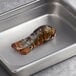A Boston Lobster Company 4-5 oz. lobster tail in a metal pan.