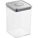 An OXO clear square plastic food storage container with a stainless steel lid.