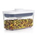 An OXO Good Grips rectangular plastic food storage container with nuts inside and a white lid.