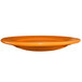 An orange International Tableware stoneware plate with a rolled edge on a white background.