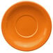 An orange stoneware saucer with a circle in the middle.