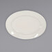 An International Tableware ivory stoneware platter with a wide, rolled edge on a gray surface.