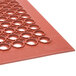 A close-up of a red rubber Notrax floor mat with holes in it.