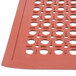 A red rubber floor mat with holes in the surface.