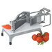 A Vollrath Redco Tomato Pro tomato slicer with slices of tomatoes next to a pile of tomatoes.