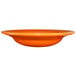 An orange International Tableware stoneware deep rim soup bowl.