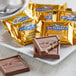 Ghirardelli Milk Chocolate Caramel Squares in gold foil packages on a plate.