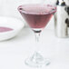 A martini glass with a Rokz Pomegranate cocktail rimmed in purple sugar.