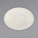 An International Tableware ivory oval serving bowl with a narrow rim on a white surface.