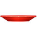 A crimson red stoneware narrow rim saucer on a table.