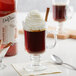 A glass of coffee with whipped cream and cinnamon sticks next to a bottle of DaVinci Gourmet Cinnamon Bark Syrup.