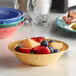 An Elite Global Solutions melamine fruit bowl filled with assorted fruit on a table.
