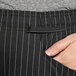 A close-up of a hand in a pocket with black pinstripes.