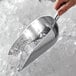 A hand holding a Vollrath cast aluminum ice scoop filled with ice.