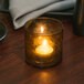 A Sterno nutmeg swirl liquid candle in a glass holder on a table.