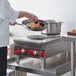 A chef cooking food in a pan on an Avantco dual countertop electric range.
