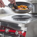 A person cooking vegetables in a pan on an Avantco dual countertop electric range.