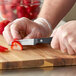 A person using a Wusthof paring knife to cut strawberries on a cutting board.
