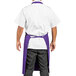 A man wearing a purple Uncommon Chef bib apron with 3 pockets.