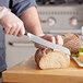 A person using a Wusthof Classic Ikon serrated bread knife to cut bread.