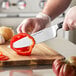 A person using a Wusthof Classic Cook's Knife to cut a red bell pepper.