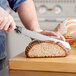 A person using a Wusthof Gourmet serrated bread knife to cut bread.