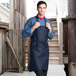 A man wearing a navy blue Uncommon Chef bib apron with three pockets.
