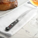 A Wusthof Classic steak knife on a plate next to a piece of meat with a glass of wine.