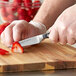 A person using a Wusthof Classic forged paring knife to cut a strawberry on a cutting board.