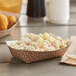 A bowl of macaroni salad in a Carnival King paper food tray on a table.