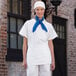 A woman wearing a white Uncommon Chef waist apron with three pockets and a blue scarf.