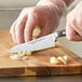 A person uses a Wusthof Classic Asian Utility Knife to cut onions on a cutting board.