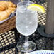 A Carlisle Alibi plastic water goblet filled with water and a lemon wedge on a table.