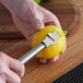 A person using an American Metalcraft stainless steel citrus zester to peel a lemon.